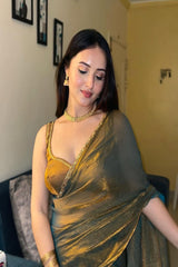 Woman wearing a green saree with gold blouse in an indoor setting
