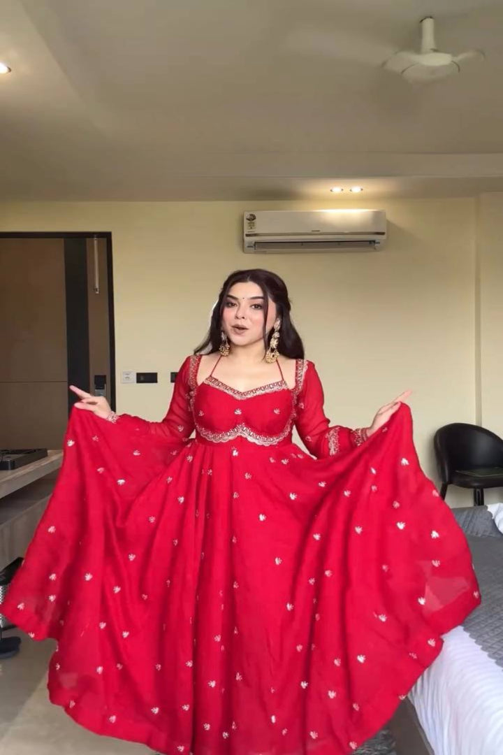 Person wearing a red traditional outfit with white patterns in an indoor setting.