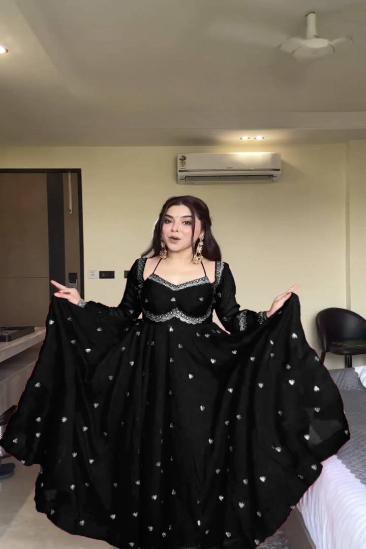 Woman wearing a black evening gown with silver embellishments in an indoor setting.