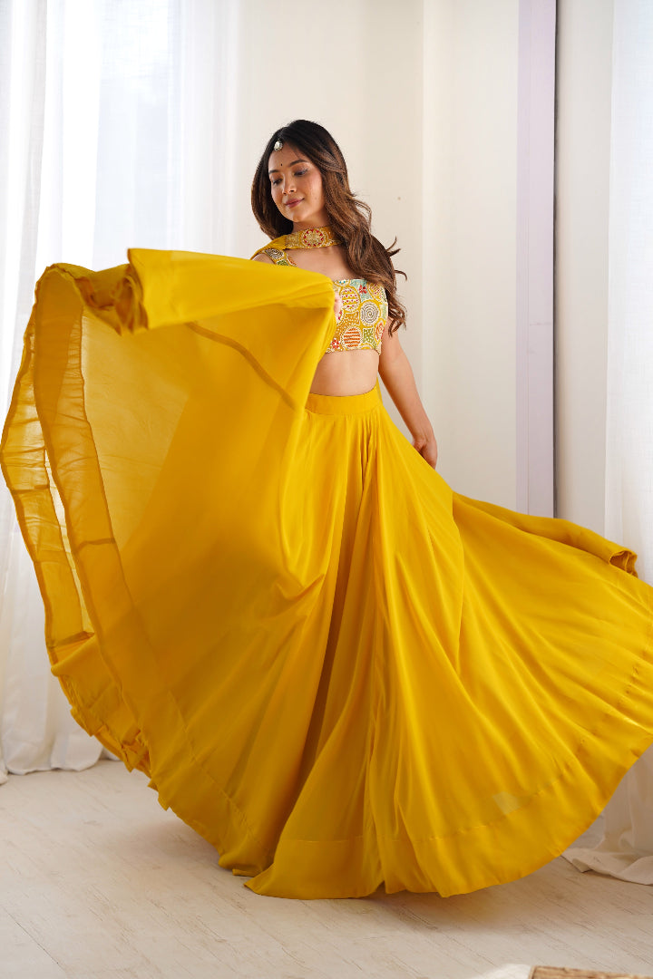 Woman in a yellow traditional outfit with a flowing skirt against a white curtain background