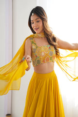 Woman in a yellow traditional outfit with a patterned top and flowing fabric.