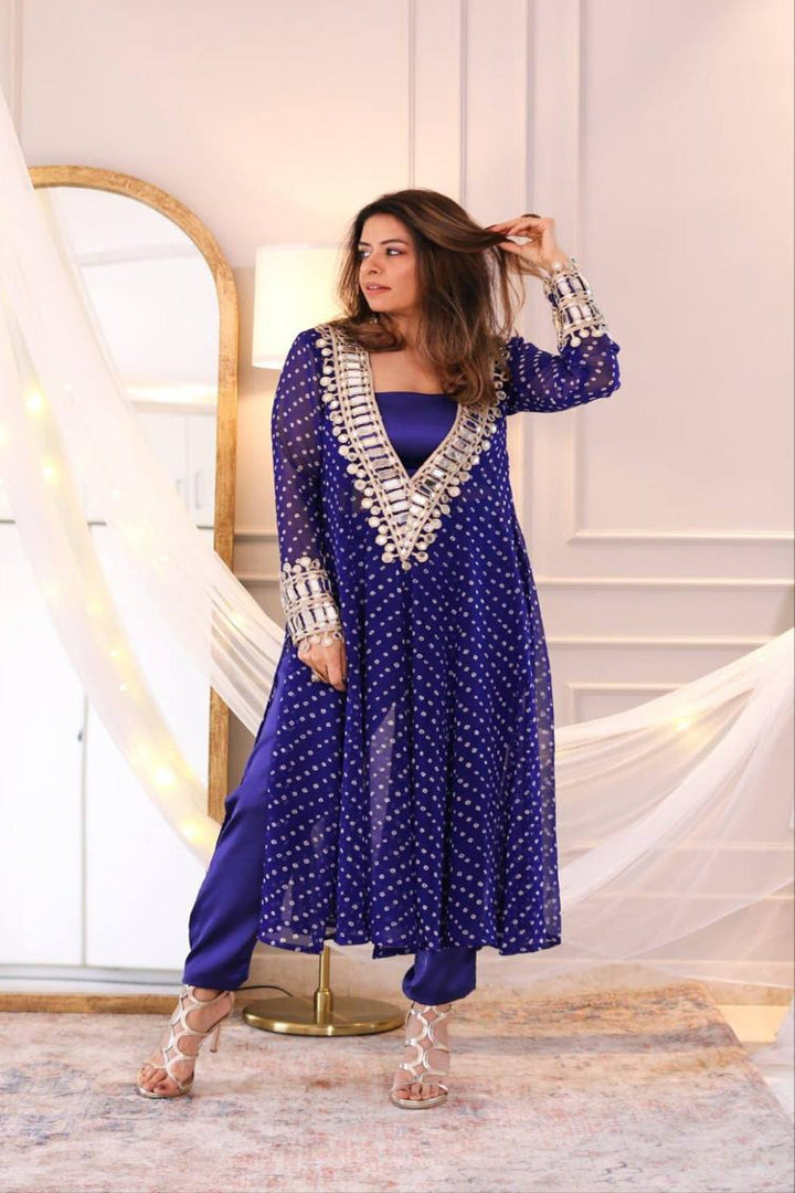 Woman in a blue traditional outfit with silver details in an elegant indoor setting.
