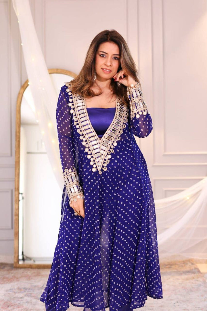 Woman wearing a blue traditional outfit with intricate designs indoors.