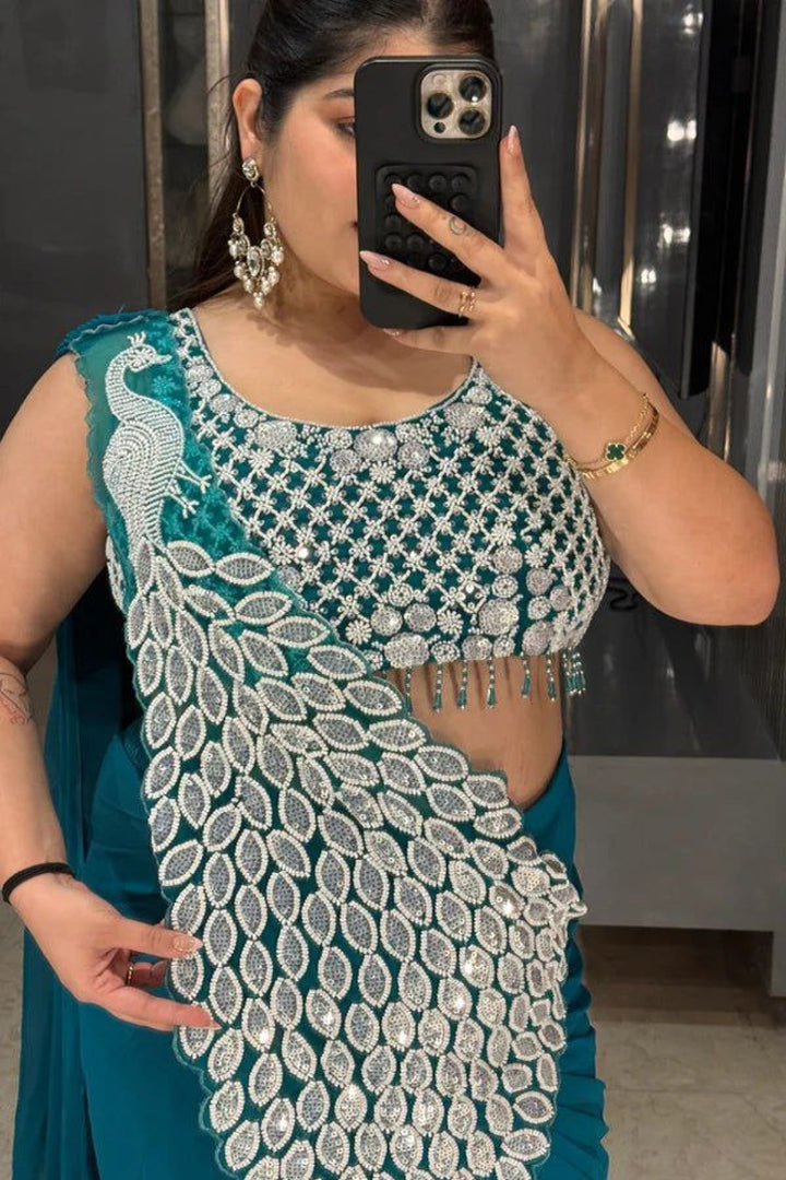 Person wearing a teal and silver embroidered outfit taking a mirror selfie.