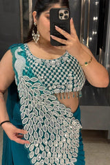 Person wearing a teal and silver embroidered outfit taking a mirror selfie.
