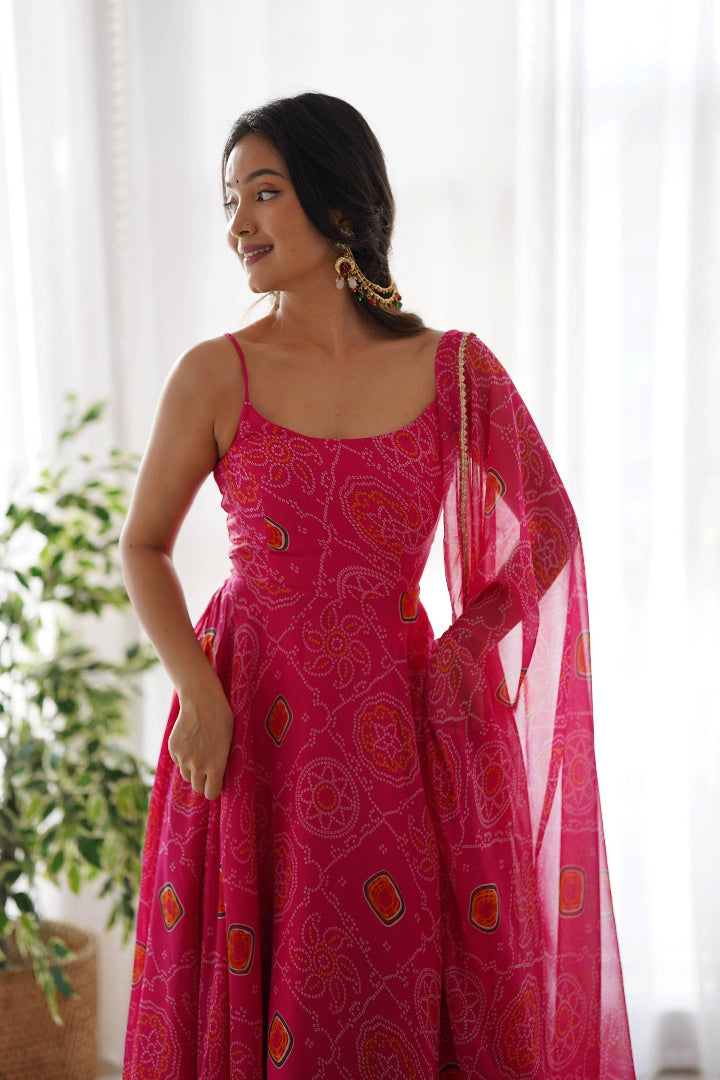 Woman wearing a pink patterned dress with a matching dupatta in a bright room.