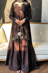 Long dark dress with floral embroidery in a room with a couch and wall art.