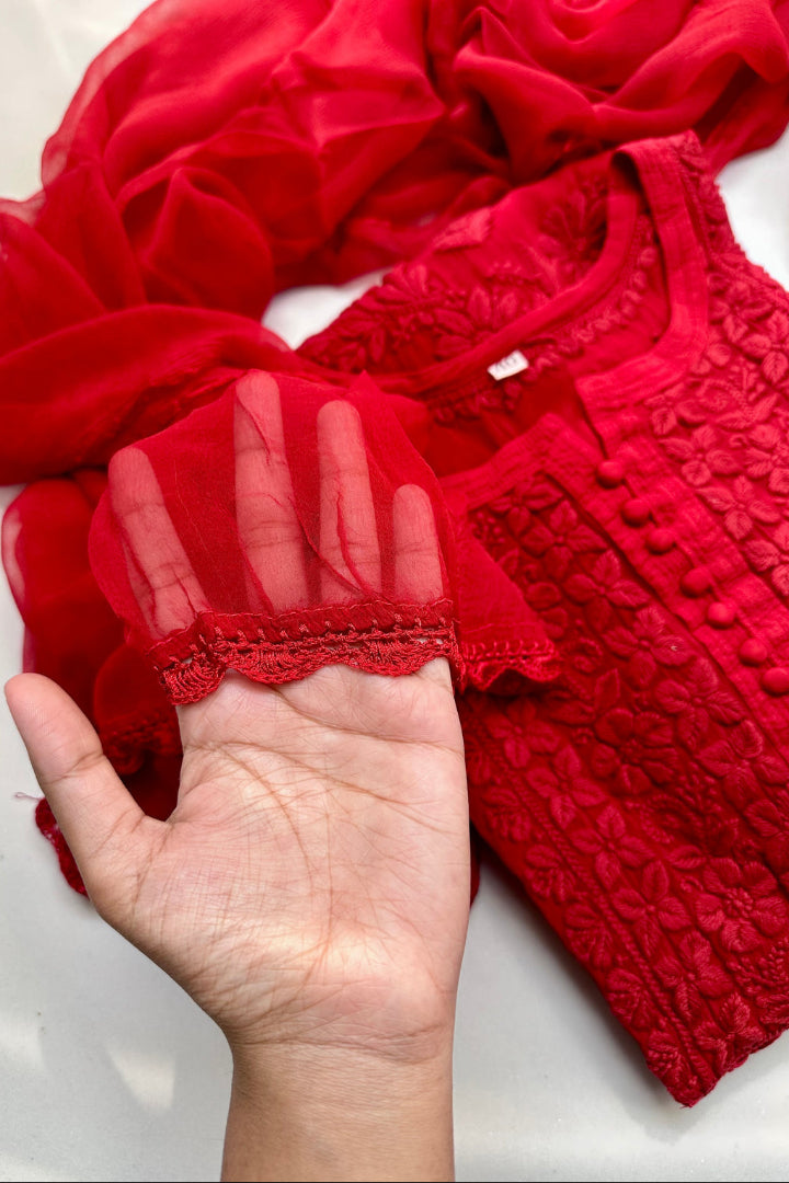 Red textured fabric with a hand holding it up for scale on a white background