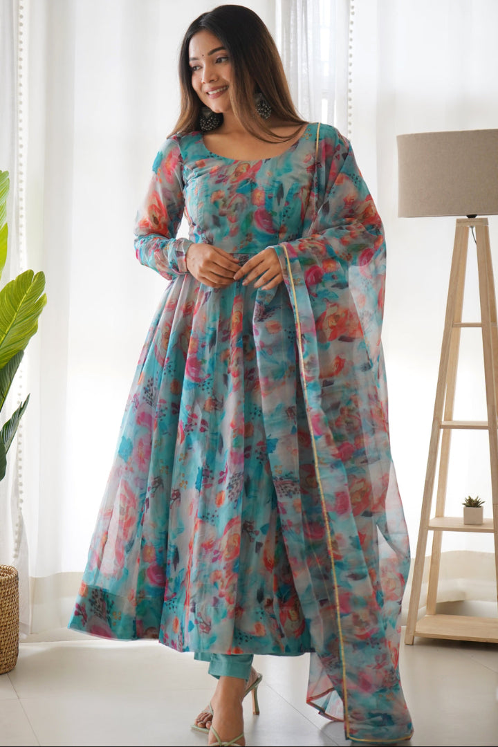 Woman wearing a colorful dress in a bright room with plants and a lamp.