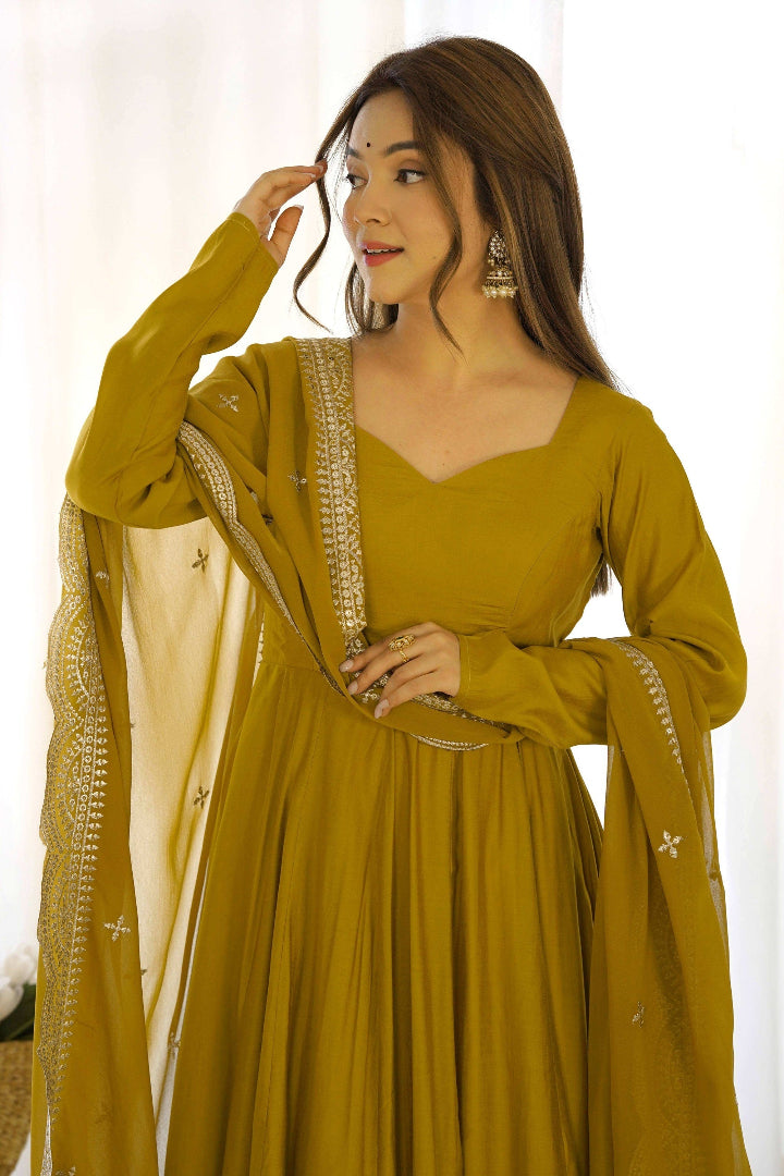 Woman wearing a mustard yellow traditional outfit with a dupatta against a white background