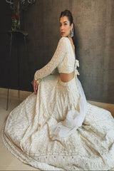 Woman in a white lace traditional outfit sitting on a couch.