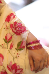Close-up of a hand wearing a ring and bangles, with floral embroidery on a garment.
