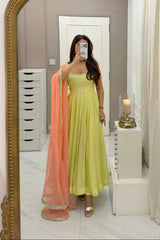 Woman in a yellow dress holding a pink dupatta in front of a large ornate mirror.