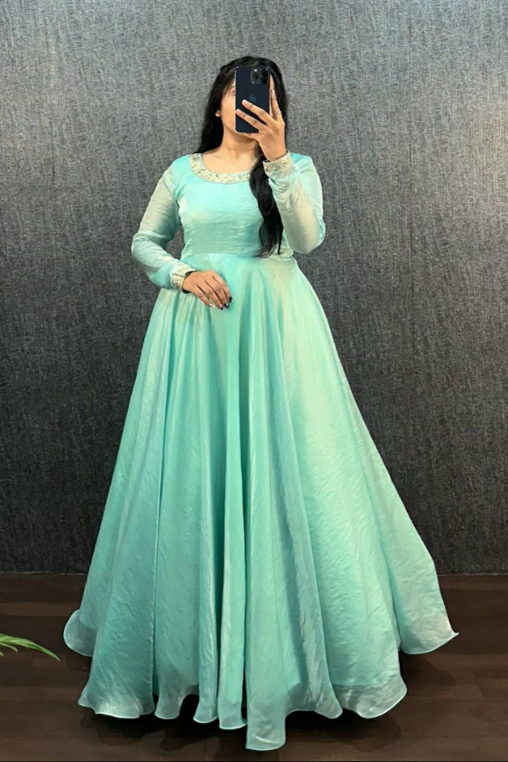 Person wearing a light blue long-sleeve dress against a dark background