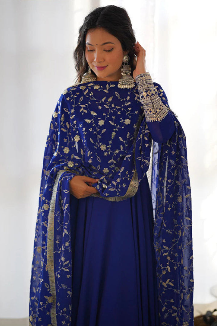 Woman wearing a blue embroidered traditional outfit with a white background