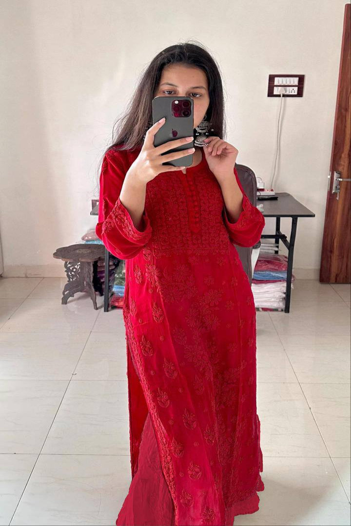 Woman taking a mirror selfie wearing a red dress in a room.