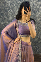 Person wearing a purple traditional outfit with a textured gray background