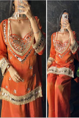 Orange traditional outfit with intricate gold embroidery on a dark background