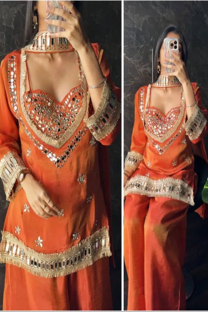 Orange traditional outfit with intricate gold embroidery on a dark background
