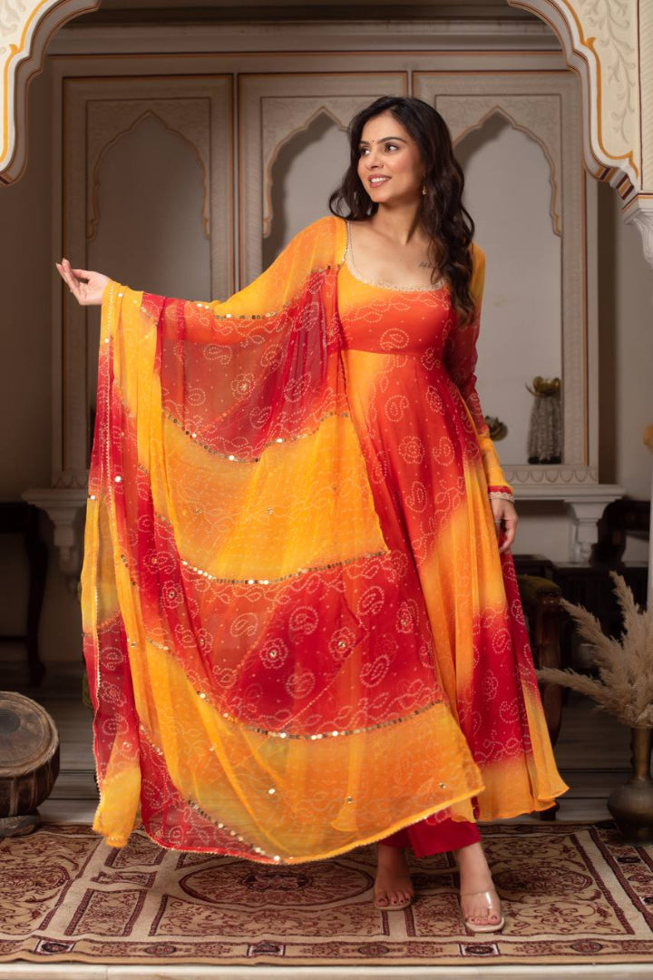 Woman in a red and orange traditional outfit with a matching dupatta in an indoor setting.