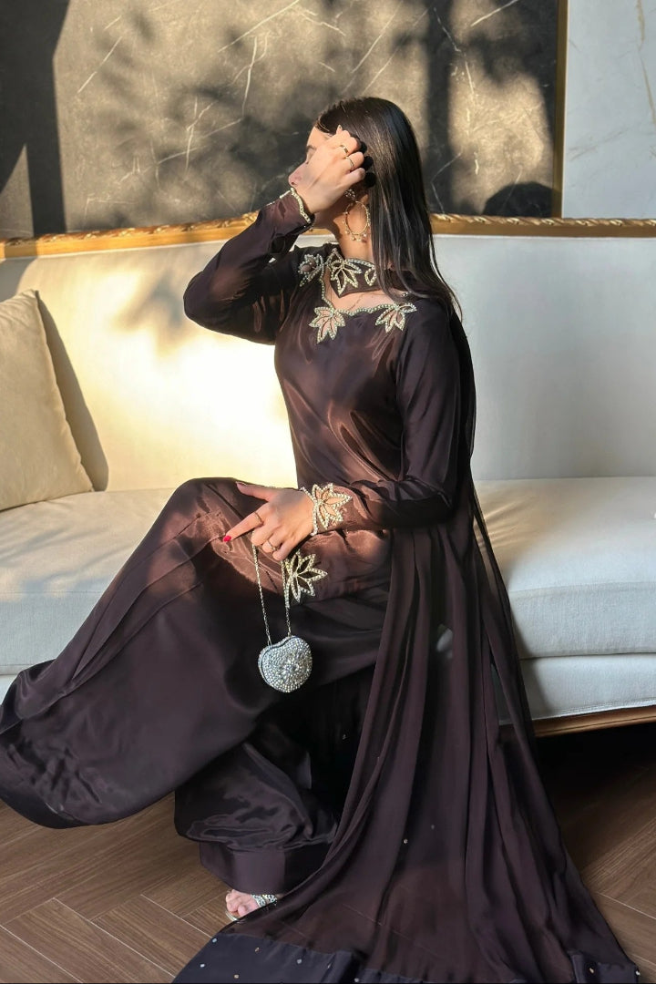 Woman in a dark dress sitting on a couch with a decorative pillow.