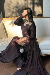 Woman in a dark dress sitting on a couch with a decorative pillow.