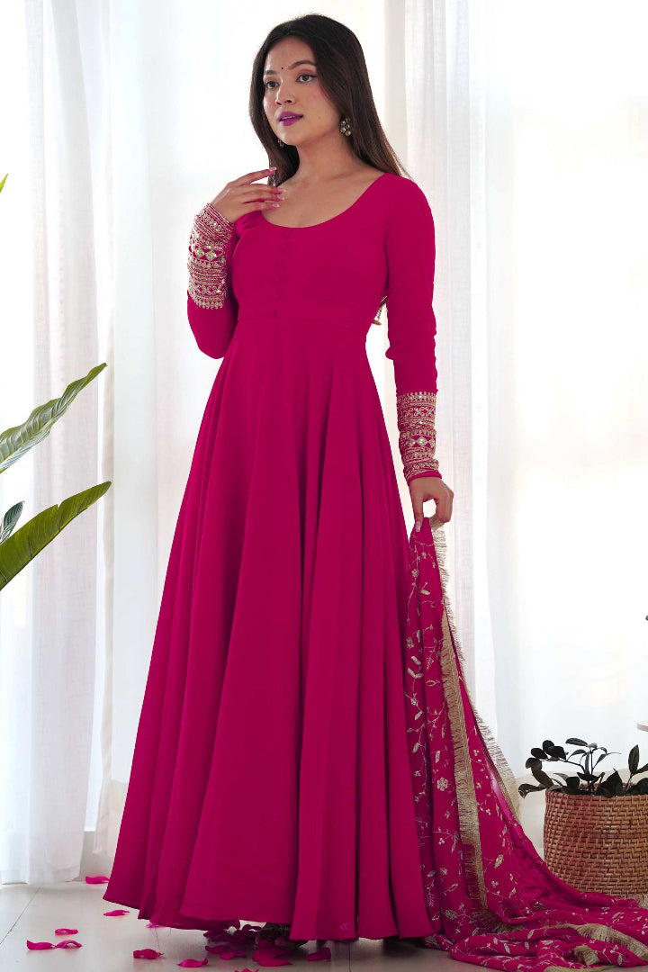 Woman wearing a pink traditional outfit with a matching dupatta in a bright room.