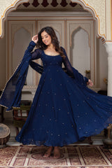 Woman in a blue dress with silver embellishments standing in an ornate room.
