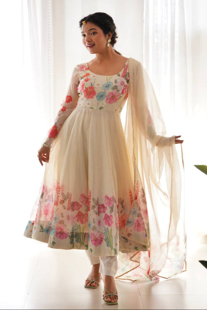 Woman wearing a floral dress with a sheer dupatta in a bright room.