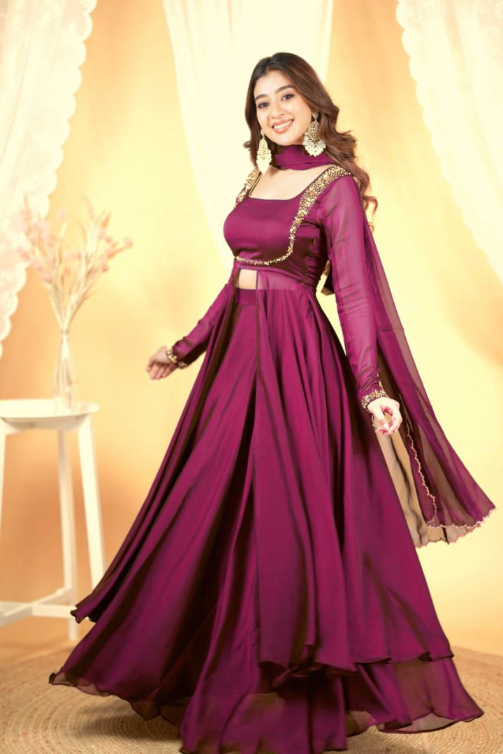 Woman wearing a long purple dress with gold accents against a warm-toned background