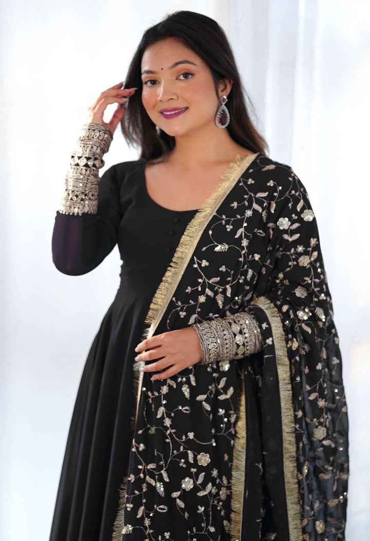 Woman wearing a black and gold traditional outfit with a white background