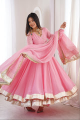 Woman wearing a pink traditional outfit with gold accents in a bright room.