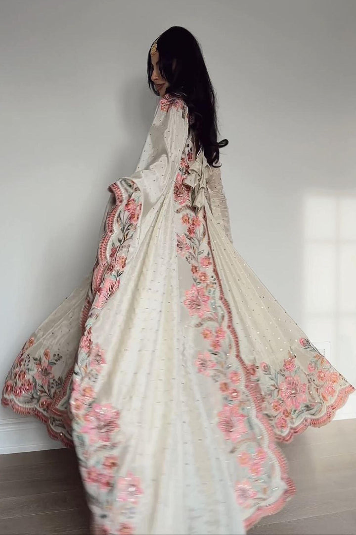 Woman wearing a floral embroidered saree against a plain background