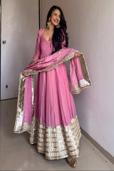 Woman in a pink traditional outfit with gold details indoors.