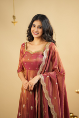 Woman wearing a traditional maroon and gold outfit with a beige background