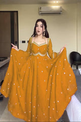 Woman in a yellow traditional outfit standing in a room with a ceiling fan and air conditioner.