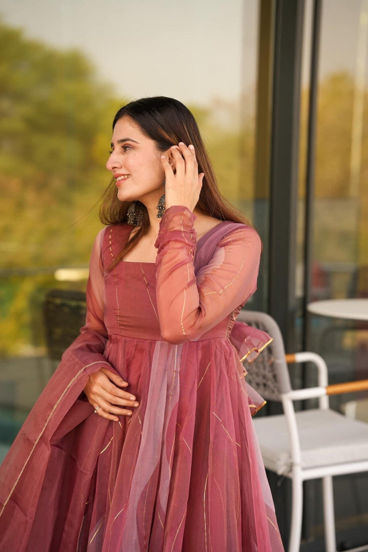Woman in a pink traditional outfit standing outdoors with blurred background