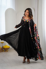 A woman modeling a black maxi dress with colorful floral embroidery 