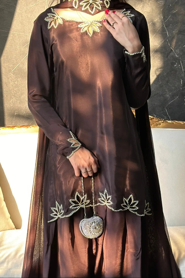 Brown dress with floral embroidery and a heart-shaped brooch on a neutral background