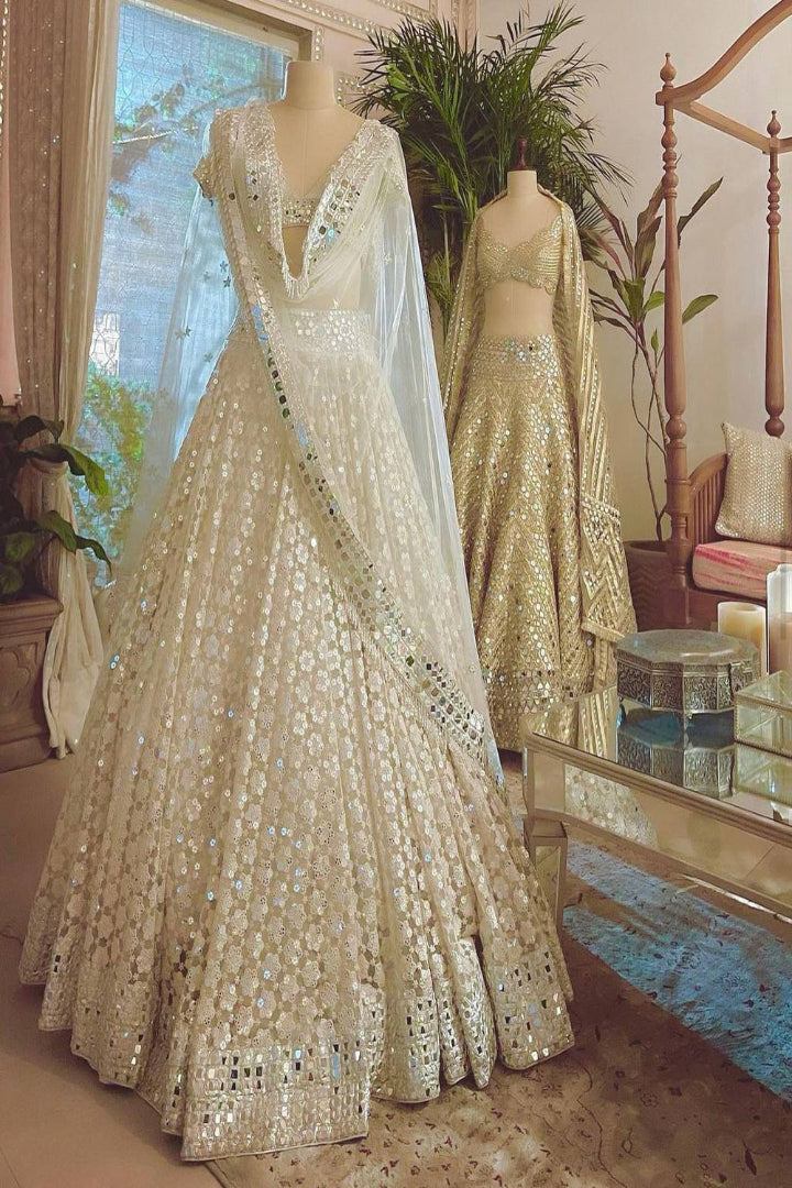 Beige embroidered lehenga with dupatta on a mannequin in a decorated room.