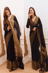 Woman wearing a black and gold saree in front of a mirror.