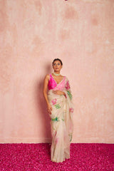 Woman wearing a floral saree with a pink blouse against a pink background