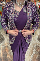 Woman wearing a purple dress with a floral jacket against a stone wall background