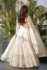 Woman in a white embroidered dress standing in front of palm trees