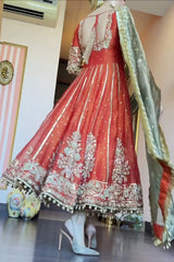 Red embroidered traditional outfit with gold details on a mannequin, paired with high-heeled shoes.