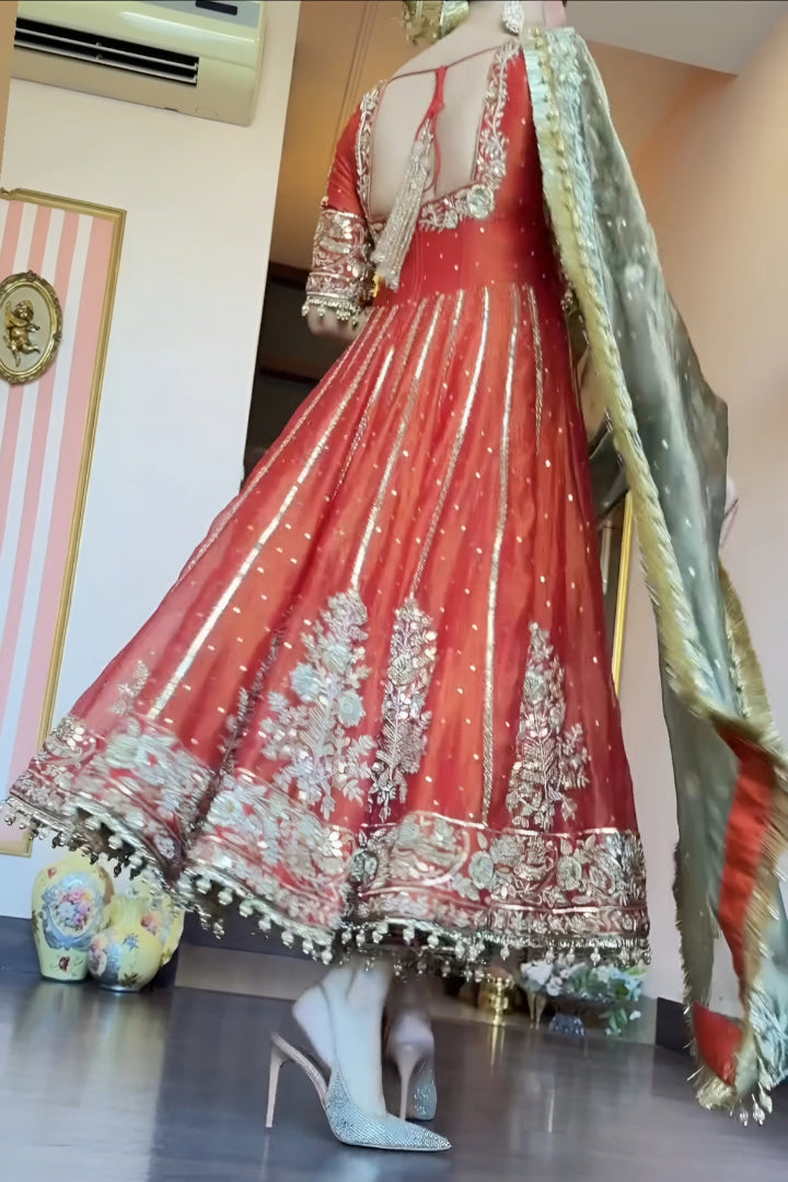 Red embroidered traditional outfit with gold details on a mannequin, paired with high-heeled shoes.