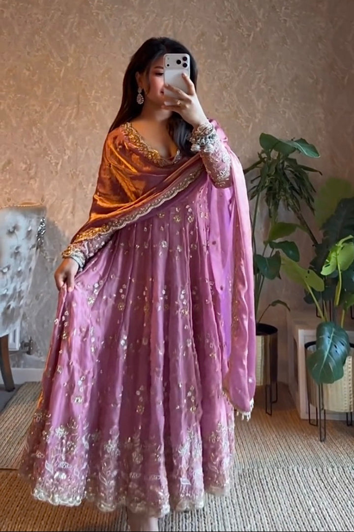 Woman in a pink and orange traditional outfit taking a mirror selfie in a room with plants.