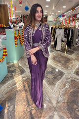 Woman in a purple traditional outfit standing in a store with clothing racks in the background.