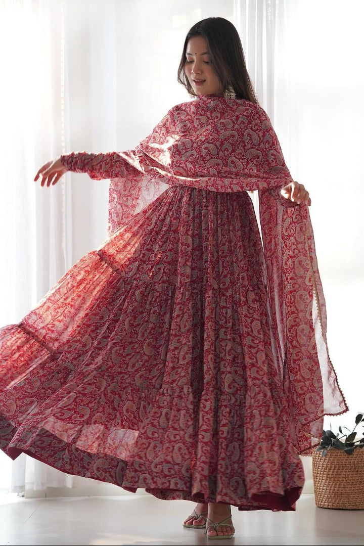 Woman wearing a red patterned dress with a matching shawl in a bright room.