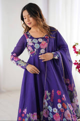 Woman wearing a purple dress with floral embroidery in a bright room.